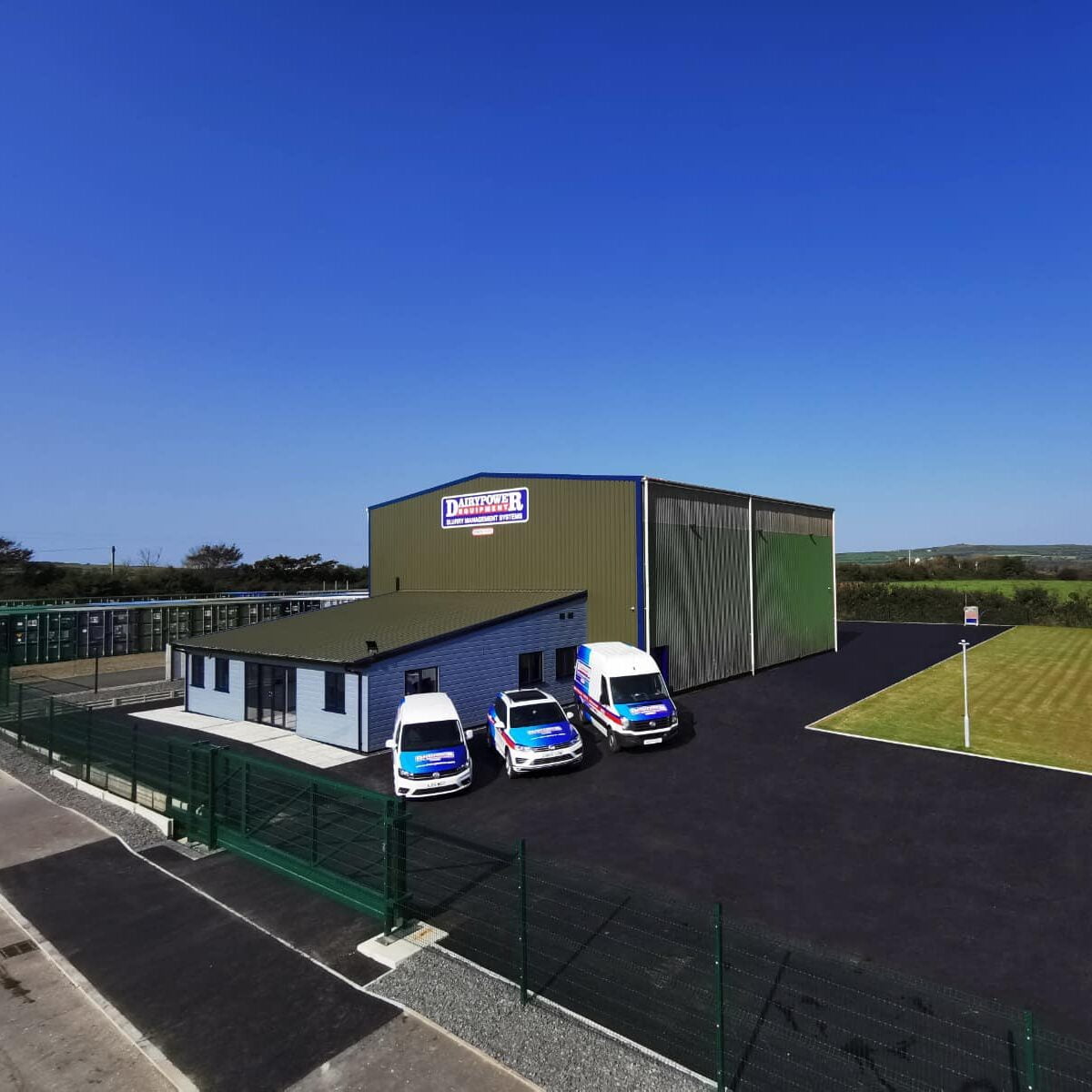 Dairy Power large shed with three branded cars outside the building on a sunny day with blue skies