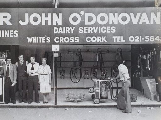 Black and white photograph of the original business with five people who work there in the foreground